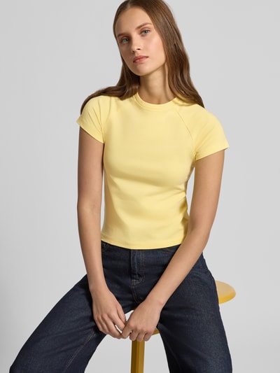 Frauenmodel trägt T-Shirt mit Raglanärmeln Modell 'KATINKA' von NOISY MAY®, gelb, eng anliegend, Rundhalsausschnitt, Nahaufnahme Oberkörper.