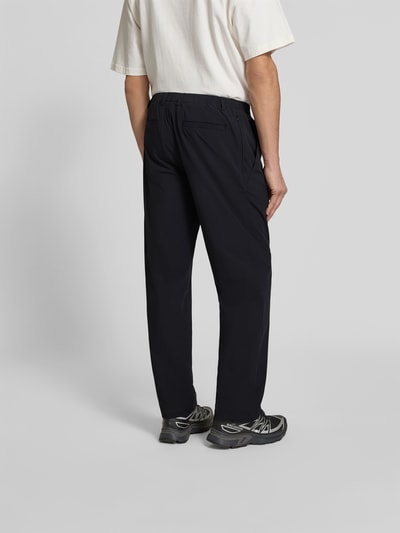 Männermodel trägt Stoffhose mit Stretch-Anteil von Forét in Schwarz, Relaxed-Fit, Elastischer-Material-Mix, Ganzkörperansicht Rückansicht.