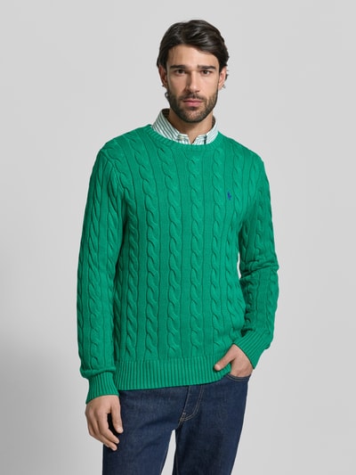 Männermodel trägt Regular Fit Strickpullover aus reiner Baumwolle von Polo Ralph Lauren in Grün, Optik: Unifarben, Strickoptik, Zopfmuster, Logo-Detail, Rundhals, Langarm, Passform: Regular-Fit, Materialverarbeitung: Strick, Ganzkörperansicht von vorne.