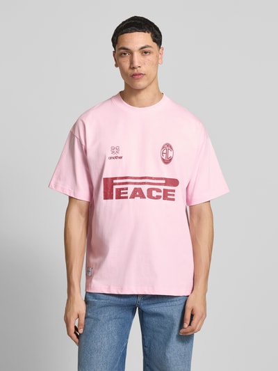 Männermodel trägt Oversized T-Shirt mit Logo-Print von ANOTHER COTTON LAB in Rosa, reine Baumwolle, Rundhalsausschnitt, Ganzkörperansicht von vorne