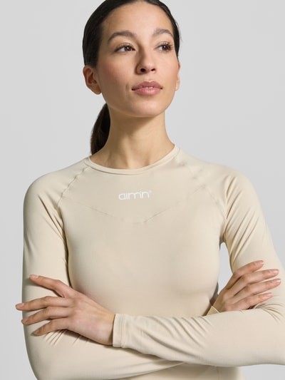 Frauenmodel trägt Langarmshirt mit Rundhalsausschnitt von aim'n in Semitransparenter-Optik, Ziernähte, Körpernah, Nahaufnahme Oberkörper. Rückenlänge bei Größe S: 55 cm.