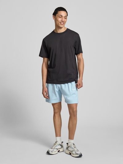 Männermodel trägt Shorts mit Logo-Stitching Modell 'ZANICA' von Ellesse aus Baumwoll-Mix in Hellblau, Relaxed-Fit, Ganzkörperansicht von vorne.