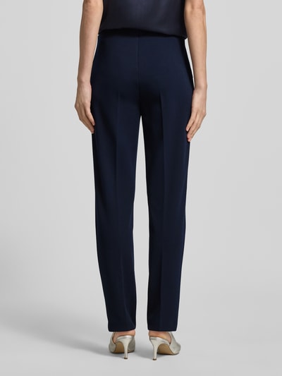 Frauenmodel trägt Slim Fit Stoffhose mit Leistentaschen von Vera Mont, elastyczna mieszanka materiałów, krój slim fit, ozdobne szwy, ciemnogranatowy kolor, kieszenie z wypustką, elastyczny pas, długość wewnętrzna nogawki 72 cm, szerokość w rozmiarze 36: 28 cm, spodnie materiałowe, Ganzkörperansicht Rückansicht.
