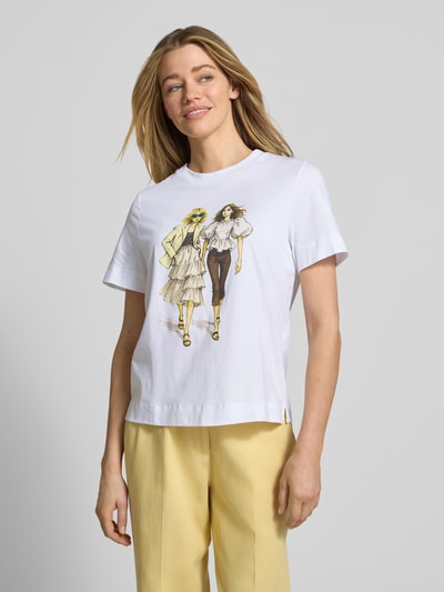 Modelka kobieca nosi T-Shirt mit Motiv-Print und Strasssteinbesatz od Rich & Royal, biała bawełna organiczna, krój straight fit, okrągły dekolt, nadruk i zdobienie z przodu, długość tyłu w rozmiarze S: 58 cm, widok całej sylwetki z przodu.