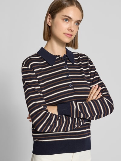 Frauenmodel trägt Poloshirt mit geripptem Saum von REVIEW, gestreiftes Muster in Dunkelblau und Beige, Material-Mix, Nahaufnahme Oberkörper.