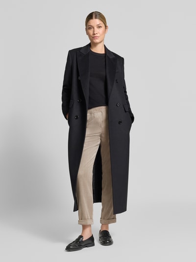 Frauenmodel trägt Cordhose mit elastischem Bund von Christian Berg Woman in Beige, kombiniert mit langem schwarzen Mantel, Ganzkörperansicht von vorne. Material-Mix mit Stretch-Anteil, Tapered Fit, elastischer Bund, seitliche Eingrifftaschen, angedeutete Gesäßleistentaschen.