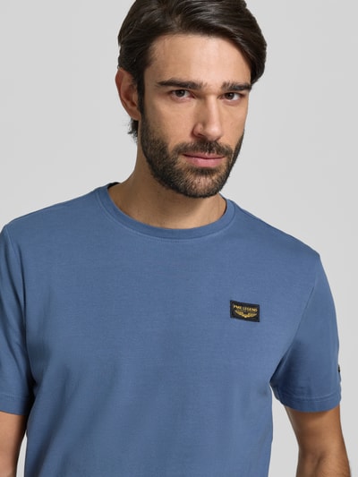 Männermodel draagt T-shirt met labeldetail van PME Legend in blauw, mix van katoen en elastaan, regular fit, ronde hals, nahaufnahme bovenlichaam. Ruglengte maat M: 71 cm.