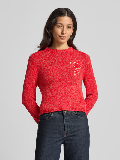 Frauenmodel trägt Slim Fit Strickpullover aus reiner Baumwolle Modell 'IGELO' von MAX&Co., Optik: Unifarben, Melange, Label-Stitching, Schleife, Rundhals, Langarm, gerippte Abschlüsse, Materialverarbeitung: Strick, Farbe Rot, melierte Textur, Cropped-Länge, Ganzkörperansicht von vorne.