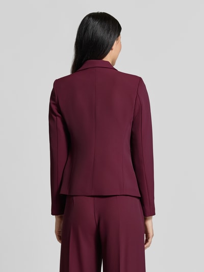 Vrouwenmodel draagt Slim Fit Blazer mit Reverskragen van Rinascimento in bordeauxrood, getailleerde pasvorm, knoopsluiting, paspelzakken, ruglengte maat S 56 cm, Ganzkörperansicht Rückansicht.