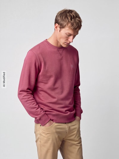 Männermodel trägt Regular Fit Sweatshirt aus reiner Baumwolle Modell 'Westart' von BOSS Orange in Dunkelrot, glatte Textur, Ganzkörperansicht von vorne, KI-modifiziertes Bild.