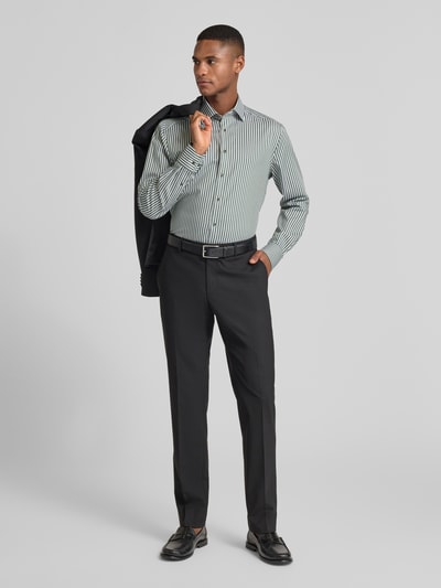 Männermodel trägt Regular Fit Businesshemd aus reiner Baumwolle mit Kentkragen von OLYMP, Längsstreifen, schwarze Hose, Ganzkörperansicht von vorne.