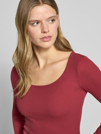Frauenmodel trägt Slim Fit Longsleeve mit tiefen Rundhalsausschnitt von Review, aus elastischem Baumwoll-Mix mit Strukturmuster, Nahaufnahme Oberkörper.