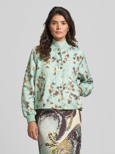 Vrouwenmodel draagt Blouson im Allover-Look mit Stehkragen van Marc Cain in mintgroen met bloemmotief, regular fit, knoopsluiting, klepzakken, ruglengte maat 36: 54 cm, schouderbreedte maat 36: 43 cm, borstwijdte maat 36: 58 cm, mouwlengte maat 36: 64 cm, geheelvooraanzicht