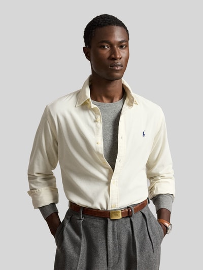 Männermodel trägt Custom Fit Freizeithemd aus reiner Baumwolle von Polo Ralph Lauren in Creme mit grauem Pullover, Nahaufnahme Oberkörper.