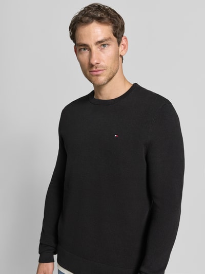 Männermodel trägt Regular Fit Pullover aus reiner Baumwolle von Tommy Hilfiger in Schwarz mit feiner Strickstruktur, Nahaufnahme Oberkörper, Herren Pullover von Tommy Hilfiger