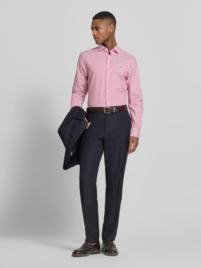 Männermodel trägt Slim Fit Businesshemd aus Baumwoll-Mix von Tommy Hilfiger Tailored, Optik: Allover-Muster, gestreift, Ganzkörperansicht von vorne.