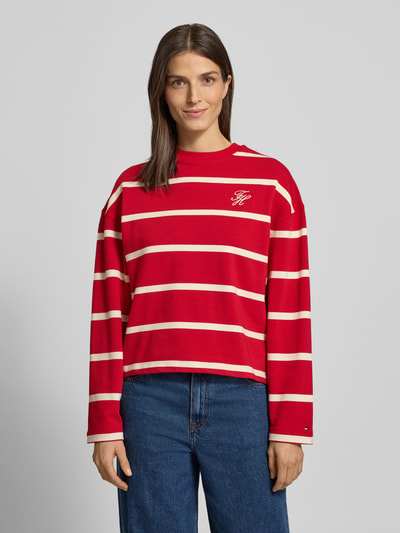 Frauenmodel trägt Relaxed Fit Sweatshirt aus Baumwoll-Mix von Tommy Hilfiger, rot mit weißem Allover-Streifendesign und Logo-Stitching, Ganzkörperansicht von vorne.