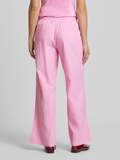Frauenmodel trägt Wide Fit Pyjama-Hose mit elastischem Bund Modell 'Poplin' von Gina Tricot in Rosa mit weißen Streifen, Ganzkörperansicht Rückansicht, Damen Pyjama-Hose mit Tunnelzug, elastischem Bund, Bundweite 36 cm, Innenbeinlänge 78 cm.
