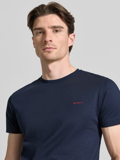 Männermodel trägt T-Shirt mit Label-Detail von Gant in Dunkelblau, reine Baumwolle, gerader Schnitt, Nahaufnahme Oberkörper.