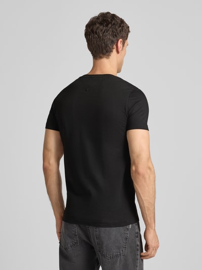 Männermodel trägt T-Shirt aus Bio-Baumwolle von Tommy Hilfiger, schwarze Farbe, gerader Schnitt, Rückenlänge 67 cm, Ganzkörperansicht Rückansicht.