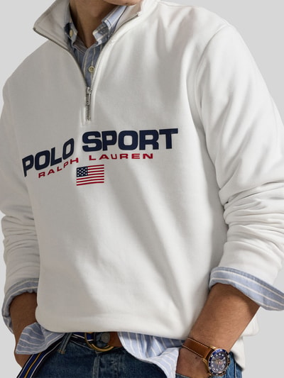 Männermodel trägt Relaxed Fit Troyer aus Baumwoll-Mix von Polo Ralph Lauren in Unifarbe Weiß mit Label Print, Nahaufnahme Oberkörper.