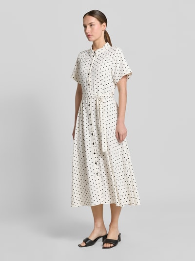 Frauenmodel trägt Hemdblusenkleid mit Bindegürtel Modell 'BlakeLL' von LOLLYS LAUNDRY, creme mit schwarzen Punkten, Taillierter Schnitt, Midikleid, Hemdblusenkragen, Knopfleiste, Ärmel mit Aufschlag, Rückenlänge bei Größe S 122 cm, Brustweite 50 cm, Ärmellänge 21 cm, Ganzkörperansicht von vorne.