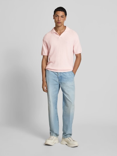 Männermodel trägt Regular Fit Poloshirt in Strick-Optik von Closed aus Baumwoll-Mix in Rosa, kurzärmelig, Ganzkörperansicht von vorne.