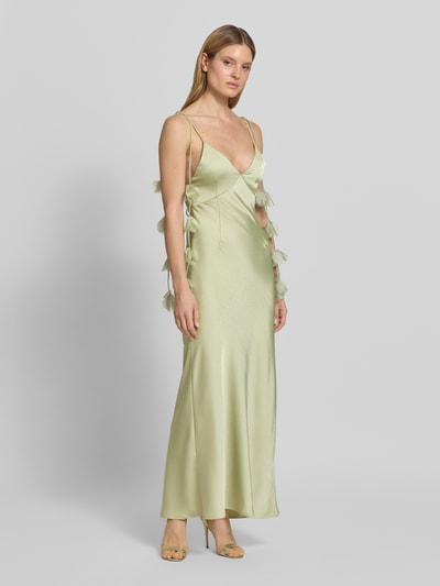 Modelka kobieca ma na sobie wieczorową sukienkę z florystycznymi detalami model 'Colly' od Neo Noir, satynowa, kolor jasny, krój slim fit, długość maxi, dekolt w serek, cienkie ramiączka, głęboki dekolt na plecach ze sznurowaniem, detale kwiatowe przy ramiączkach, szerokość w rozmiarze 36: 22 cm, długość tyłu w rozmiarze 36: 132 cm, widok całej sylwetki z przodu.