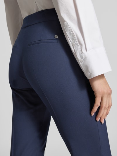 Kobiece modelka nosi Regular Fit smukłe spodnie z domieszką wiskozy model 'HILESA' od HUGO, gładka granatowa faktura piqué, detal tylnych kieszeni, zdjęcie z tyłu zbliżenie bioder.
