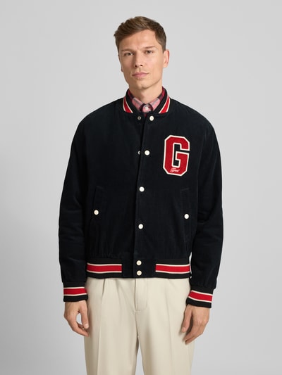 Männermodel trägt College-Jacke aus Cord mit Label-Detail von Gant in Schwarz, Regular-Fit, Stehkragen, Knopfleiste, Eingrifftaschen, reine Baumwolle, Vorderansicht Oberkörper