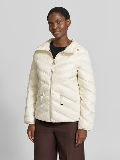 Vrouwenmodel draagt Steppjacke mit Stehkragen und Reißverschlusstaschen van Christian Berg Woman Selection in crème met goudkleurige ritsen, regular fit, voorzijde met steekzakken en opstaande kraag, medium gewatteerde textuur, voorkant schuin zicht, Ganzkörperansicht von vorne. Context: ruglengte maat 36: 61 cm, schouderbreedte: 42 cm, borstwijdte: 51 cm, mouwlengte: 58 cm.