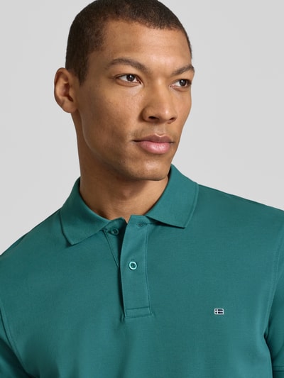 Männermodel trägt Regular Fit Poloshirt mit Stitching von Christian Berg Men in Grün aus reiner Baumwolle mit Knopfleiste, Nahaufnahme Oberkörper.