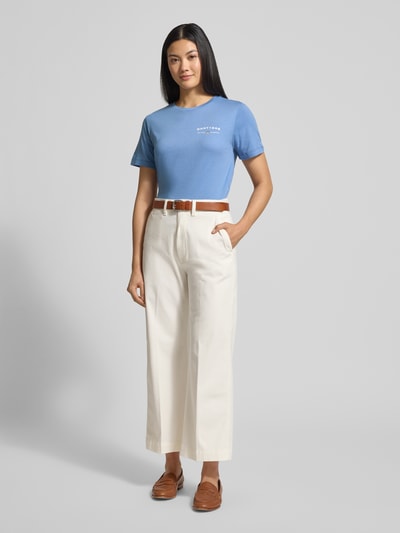 Kobieta modelka nosi T-shirt z nadrukiem logo i okrągłym dekoltem od Gant, bawełna, regular fit, kolor niebieski, widok całej sylwetki z przodu.