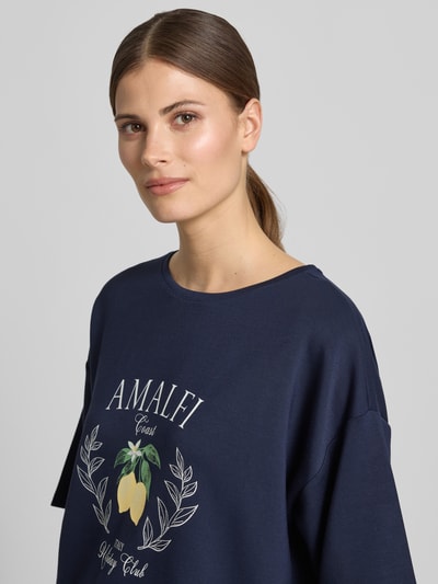 Frauenmodel trägt Relaxed Fit T-Shirt mit Logo-Print von Christian Berg Woman aus Elastischer-Material-Mix mit Modal-Anteil und Rundhalsausschnitt, dunkelblau, Nahaufnahme Oberkörper.