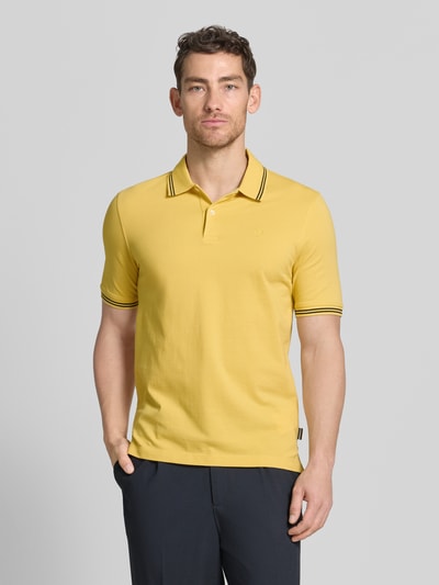 Männermodel trägt Regular Fit Poloshirt mit Logo-Stitching von bugatti, Reine Baumwolle, Polokragen, Knopfleiste, Label-Detail, Ganzkörperansicht von vorne.