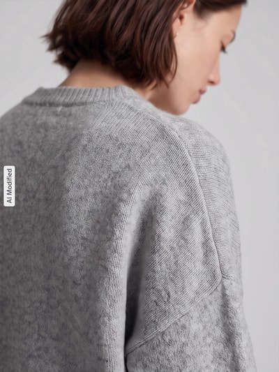Vrouwenmodel draagt oversized pullover met wol model 'BOOM' van VERO MODA in lichtgrijs met grove textuur, detailopname, KI-modificeerd beeld.