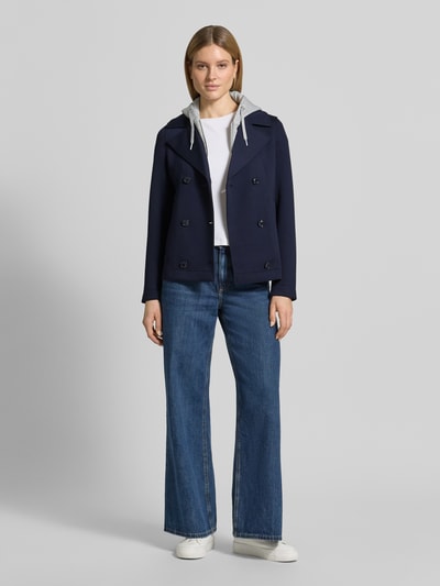 Modelka nosi Regular Fit Sweatjacke mit Viskose-Anteil od s.Oliver RED LABEL, granatowa, dwurzędowa listwa guzikowa, kaptur, krój regular fit, wpuszczane kieszenie, wykończenie materiału z dzianiny dresowej, widok całej sylwetki z przodu.