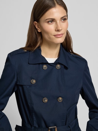 Frauenmodel trägt Regular Fit Mantel mit Umlegekragen Modell 'Lora' von Soyaconcept, dunkelblauer Material-Mix mit Baumwoll-Anteil, 2-reihige-Knopfleiste, taillierte Passform, abnehmbarer Stoffgürtel, Eingrifftaschen, Nahaufnahme Oberkörper.