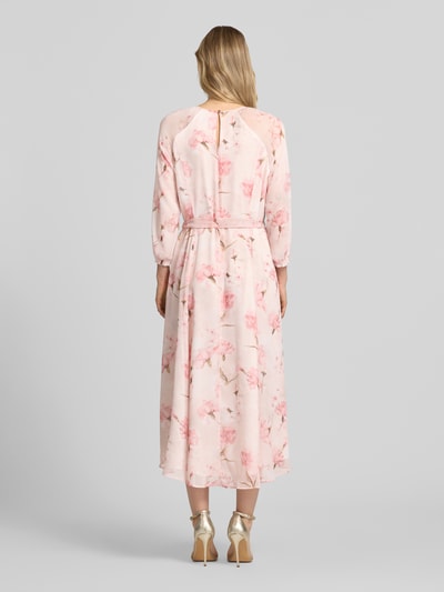 Modelka kobieca nosi Midikleid mit Bindegürtel von More & More, lekka różowa tkanina z kwiatowym wzorem, krój slim fit, okrągły dekolt z wycięciem, ozdobny pasek, rękaw 3/4, zapięcie na zamek i dziurkę z tyłu, długość tyłu w rozmiarze 36: 128 cm, szerokość w rozmiarze 36: 42 cm, długość rękawa w rozmiarze 36: 58 cm, pełen tylny widok.