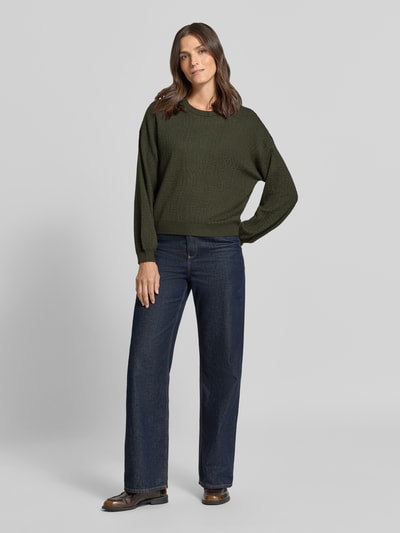 Modelka kobieca ma na sobie sweter Regular Fit Pullover aus Viskose-Mix model 'NANCY' od VERO MODA w kolorze ciemnej zieleni, faktura dzianiny, do tego ciemnoniebieskie proste jeansy, damski sweter VERO MODA, widok całej sylwetki z przodu.