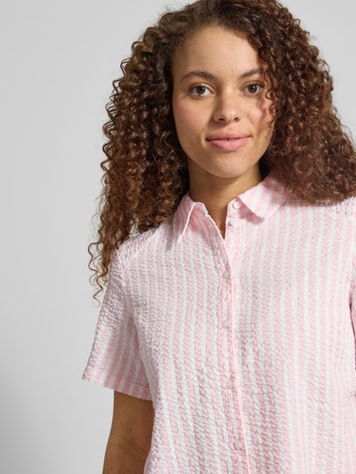 Frauenmodel trägt Regular Fit Hemdbluse aus reiner Baumwolle Modell 'TINNA' von Pieces mit rosa-weißem Allover-Muster, Nahaufnahme Oberkörper.