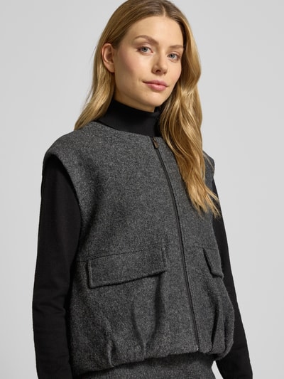 Vrouwenmodel draagt Weste mit Reißverschluss Modell 'Womaya' van OPUS in grijze viscose-wolmix met ronde hals en klepzakken, regular fit, detailopname bovenlichaam.