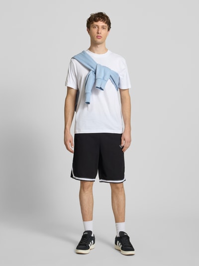 Männermodel trägt Shorts mit Logo-Stitching Modell 'Signar' von Pegador in Schwarz mit Kontraststreifen, Reine Baumwolle, Gerader-Schnitt, Ganzkörperansicht von vorne.