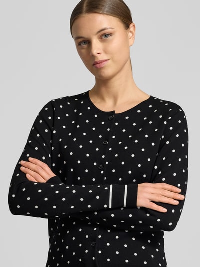 Frauenmodel trägt Regular Fit Cardigan aus Viskose-Mix Modell 'Karli' von JOOP! in Strick-Optik mit Rundhalsausschnitt und Logo-Stitching, Farbe Schwarz mit weißen Punkten, Nahaufnahme Oberkörper.
