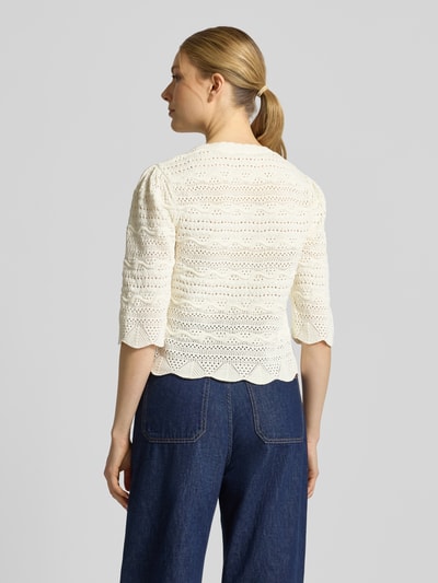 Modelka kobieca ma na sobie Strickjacke mit Rundhalsausschnitt Modell 'GANACH' od SUNCOO PARIS, czysta bawełna, krój regular fit, kremowy kolor, faktura ażurowa, zapięcie na guziki, długość pleców 52 cm, długość rękawa 34 cm, widok całej sylwetki z tyłu.