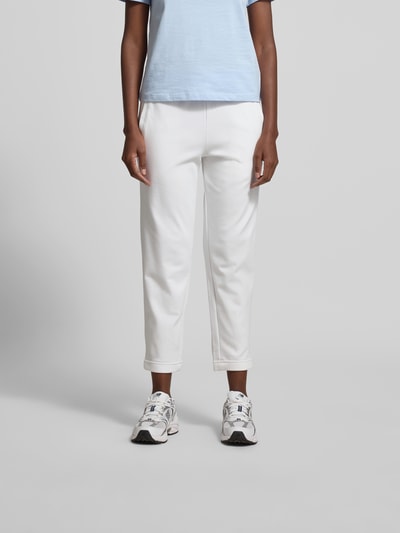 Frauenmodel trägt Sweatpants aus Baumwoll-Mix von Juvia, schmal zulaufendes Bein, elastischer Bund mit Tunnelzug, Eingrifftaschen, elastische Abschlüsse, Farbe Weiß, glatte Textur, Ganzkörperansicht von vorne.