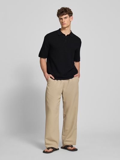 Männermodel trägt Relaxed Fit Poloshirt Modell 'FERDINAND' von Redefined Rebel aus Reine Baumwolle, Schwarz, Strickshirt, Knopfleiste, Ganzkörperansicht von vorne. Rückenlänge bei Größe M: 70 cm.