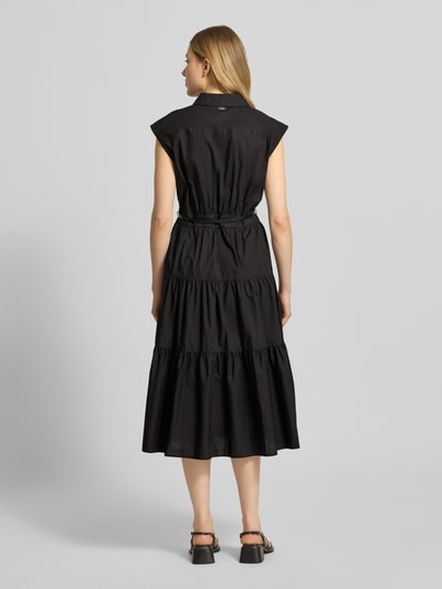 Frauenmodel trägt Hemdblusenkleid mit Gürtel und Knopfleiste von MICHAEL Michael Kors, schwarz, reine Baumwolle, Volantsaum, taillierter Schnitt, Ganzkörperansicht Rückansicht.