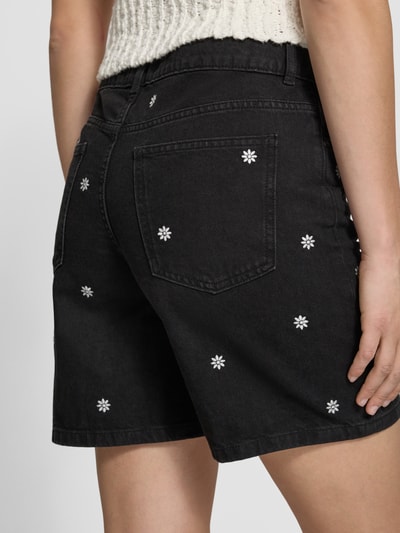 Frauenmodel trägt Schwarze Jeansshorts mit Stitchings von REVIEW aus reiner Baumwolle, Regular Fit, schwarze Farbe mit weißen Ziernähten, Eingrifftaschen, Detailaufnahme Rückansicht.
