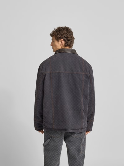 Männermodel trägt Jacke mit echtem Rindsleder-Besatz von DAILY PAPER in Dunkelgrau, entspannte Passform, Baumwolle, Rückansicht, Ganzkörperansicht.